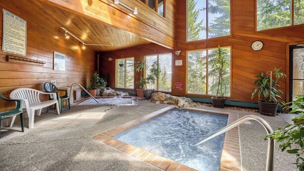 Een wellnessruimte met een jacuzzi, zitplaatsen en potplanten.
