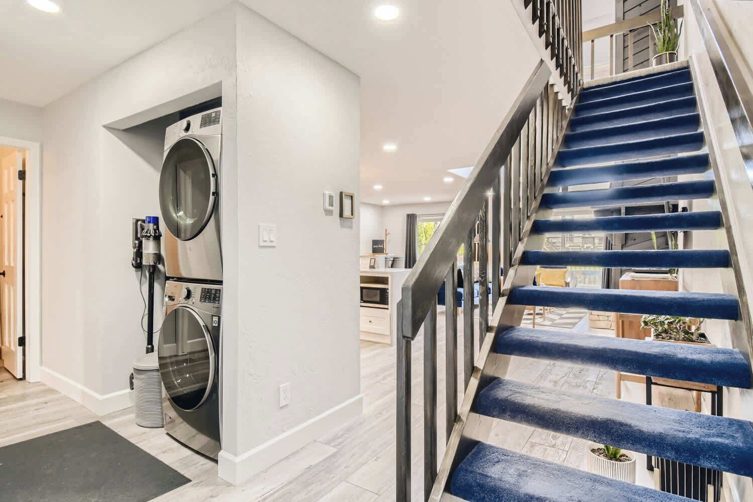 Un intérieur moderne avec un escalier, un lave-linge et un coin cuisine.