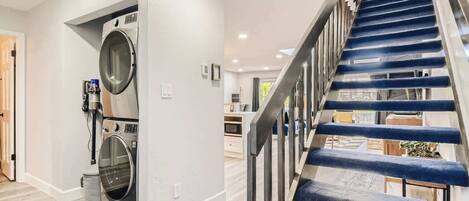 Un intérieur moderne avec un escalier, un lave-linge et un coin cuisine.
