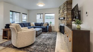 Ein Wohnzimmer mit Ecksofa, einem runden Sessel, einem Kamin und einer Wand aus Stein.
