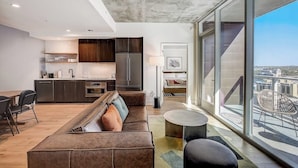 Un appartement moderne doté d’une cuisine, d’un espace de vie et de grandes fenêtres offrant une vue sur la ville.