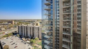 Un immeuble de grande hauteur doté de nombreux balcons, d’un parking et offrant une vue dégagée sur le paysage urbain environnant.