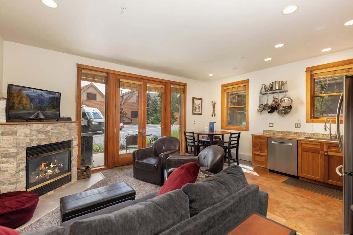 A modern living room with a fireplace, leather sofas, and a dining area with a view of the outside.