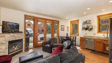 A modern living room with a fireplace, leather sofas, and a dining area with a view of the outside.