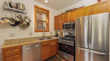 A kitchen with stainless steel appliances, wooden cabinets, a dish rack, and a window.