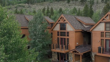 A cluster of wooden cabins with balconies, set against a mountainous backdrop.