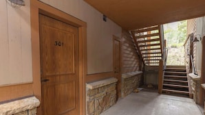 A wooden door with the number 301, a stone wall, a concrete floor, and a wooden staircase leading outside. - Sunny 2br/2ba Bedroom Condo on the Road to Keystone (Keystone)