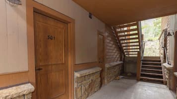 A wooden door with the number 301, a stone wall, a concrete floor, and a wooden staircase leading outside.