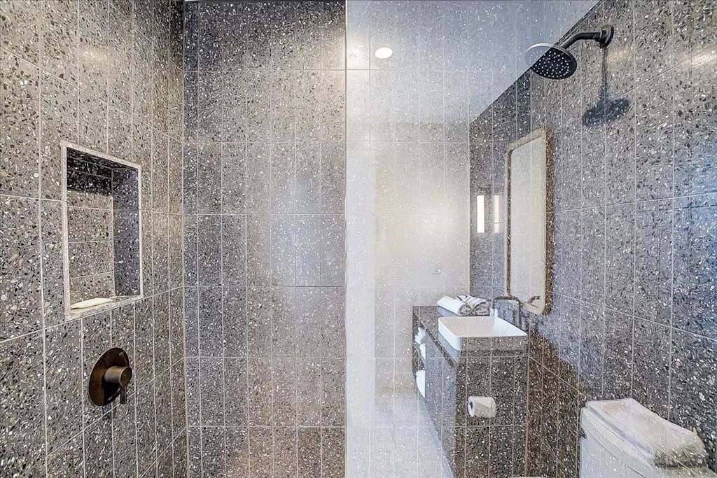 A modern bathroom with a shower, a sink, and a mirror.