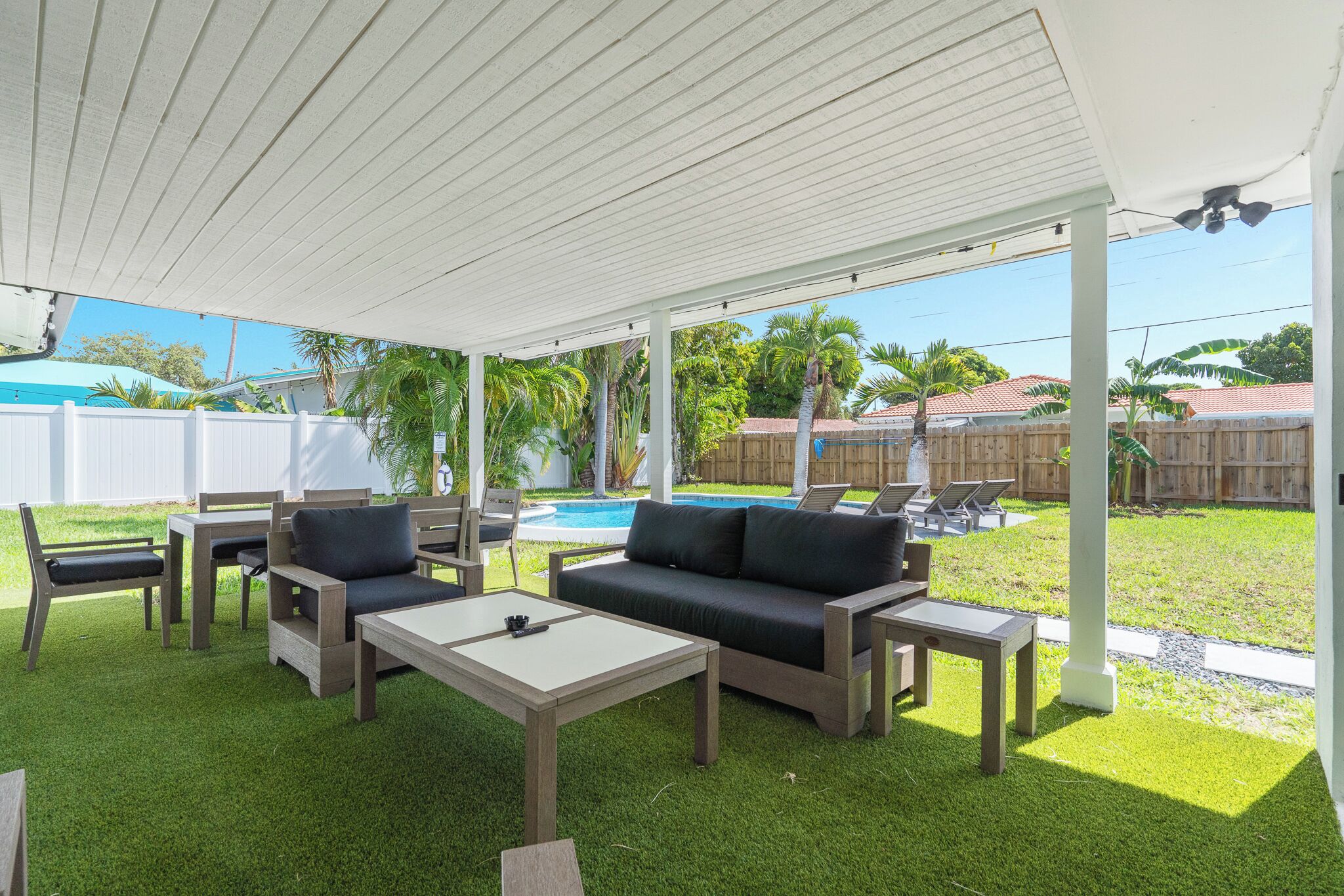 A covered patio area with outdoor furniture, a pool, and a view of the backyard.