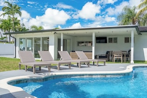 A pool area with lounge chairs and a covered seating area. - Delila's Chic 3br 2ba with Heated Pool (Deerfield Beach)