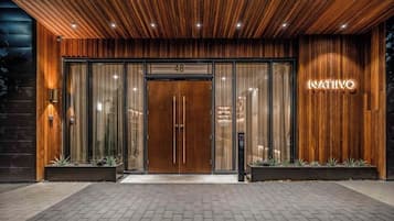 A modern building with a wooden facade, a large entrance with glass doors, and a sign that reads 'NATIVO'.