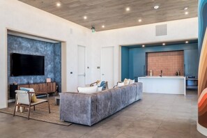 A modern living area with a sofa, TV, and kitchen in the background. - Luxury 28th Flr Luxe Condo, Balcony Views, Dog-Friendly (Austin)