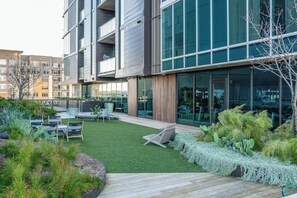 A modern building with a courtyard, outdoor seating, and a variety of plants.