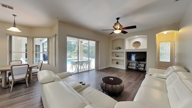 A spacious living room with a large sofa, a coffee table, and a ceiling fan. - Sunrise Paradise (Port Orange)