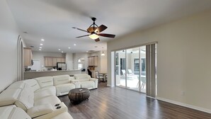 A spacious living room with a sectional sofa, a coffee table, and a ceiling fan. - Sunrise Paradise (Port Orange)