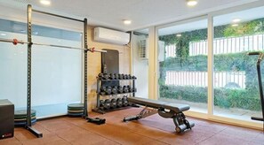 Ein Fitnessraum mit Hantelgestell, Bank, Kurzhanteln und Laufband.