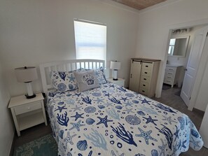 Ein Schlafzimmer mit einem Bett, Nachttischen, einer Kommode und einem Fenster.
