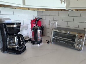 Eine Küche mit Kaffeemaschine, Wasserspender, Toaster und Feuerlöscher.