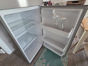 Ein offener Kühlschrank mit übersichtlichen Aufbewahrungsbehältern sowie eine Küchenarbeitsplatte mit einem Toaster und weiteren Geräten.