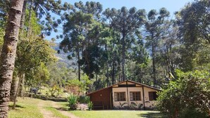 A single-story building with a sloped roof, surrounded by dense forest. - Sítio Salamandra (Aiuruoca)