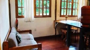 A wooden-floored room with a sofa, a table, and a fireplace. - Sítio Salamandra (Aiuruoca)
