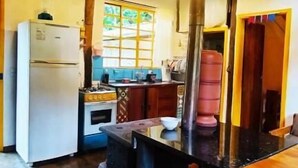 A rustic kitchen with a wooden ceiling, a refrigerator, a stove, and a sink. - Sítio Salamandra (Aiuruoca)