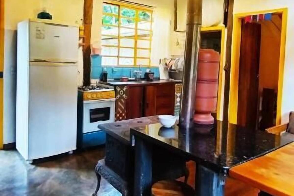 A rustic kitchen with a wooden ceiling, a refrigerator, a stove, and a sink.