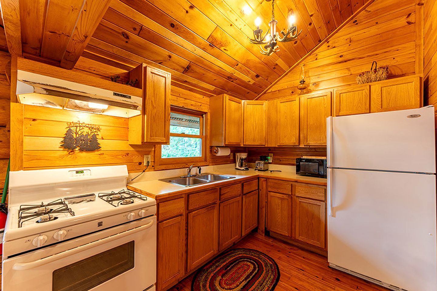 Ein Interieur einer Holzhütte mit Ofen, Spüle, Kühlschrank und Holzschränken.