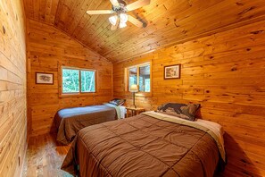 A cabin with two beds, wooden walls, and a ceiling fan. - Secluded Pet-Friendly Cabin Rental on Big Lake for Dreamy Glamping in Ely, MN (Ely)