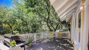 Eine überdachte Terrasse im Freien mit Grill, Stühlen und Blumentöpfen.