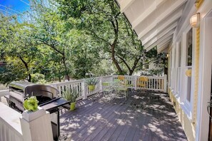 A covered outdoor deck with a grill, chairs, and potted plants. - Quiet central home with enclosed yard, deck, grill, central AC, & washer/dryer (Austin)
