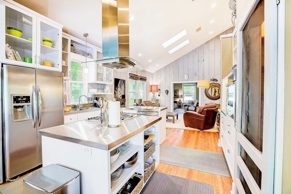 A modern kitchen with a central island, built-in cabinets, and a dining area with a sofa. - Quiet central home with enclosed yard, deck, grill, central AC, & washer/dryer (Austin)