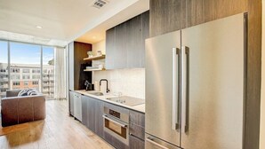 Une cuisine moderne dotée d’appareils électroménagers en acier inoxydable, d’une grande fenêtre et offrant une vue sur la ville.