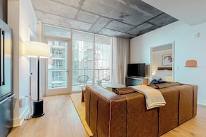 A modern living room with a sofa, a television, and a dining area. - Downtown Austin Luxe condo w/private balcony - rooftop pool & gym (Austin)