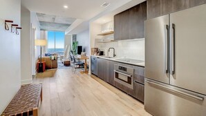 Una cocina moderna con electrodomésticos de acero inoxidable, un banco de madera y vistas al exterior.