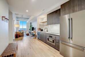 A modern kitchen with stainless steel appliances, a wooden bench, and a view to the outside. - Rainey St. condo with balcony, rooftop pool, fitness center and coffee shop (Austin)