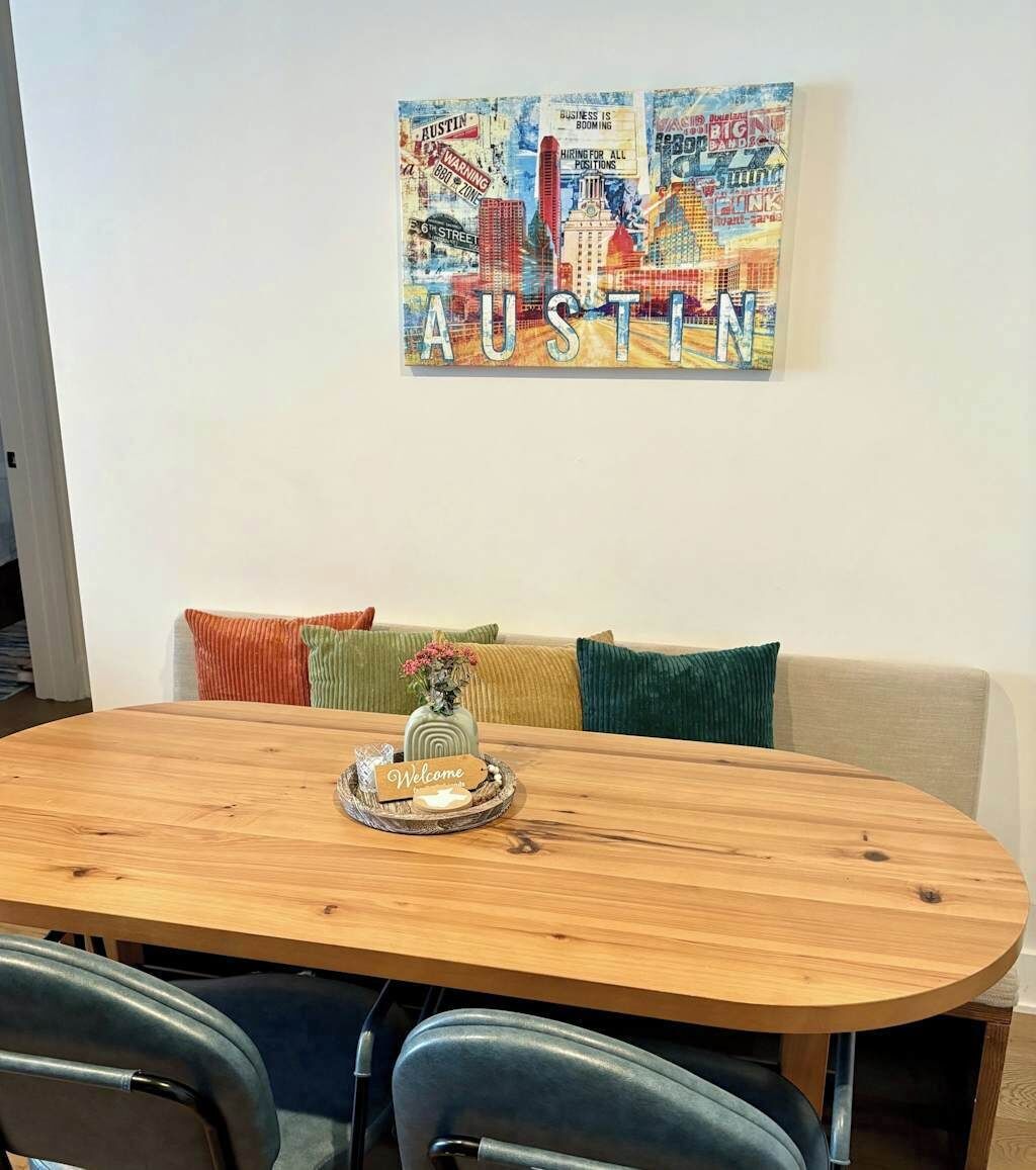 A dining area with a wooden table, a vase with flowers, and a 'Welcome' sign.