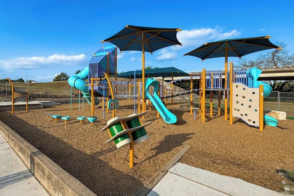 A playground with slides, climbing structures, and shaded areas.