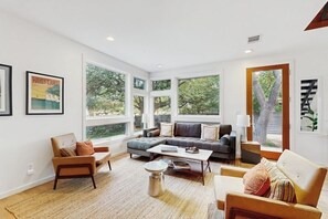 A spacious living room with large windows, a sectional sofa, a coffee table, and a fireplace. - Stunning dog-friendly house w/private gas grill & deck -steps to South Congress (Austin)