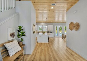 Una cocina moderna con suelo de madera, armarios blancos y una isla central.