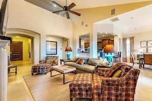 A spacious living room with a high ceiling, a ceiling fan, and a kitchen in the background. - Waterfront All-Suite w/ Private Balcony – On-Site Dining, Spa & Marina (Lakeway)