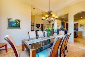 A dining area with a long table, chairs, a chandelier, and a painting on the wall. - Waterfront All-Suite w/ Private Balcony – On-Site Dining, Spa & Marina (Lakeway)