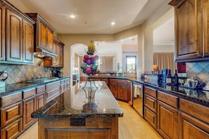 A spacious kitchen with wooden cabinets, a granite countertop, and a central island. - Waterfront All-Suite w/ Private Balcony – On-Site Dining, Spa & Marina (Lakeway)