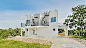Un bâtiment moderne à deux étages, doté d’un escalier central, d’un porche couvert et d’un jardin paysager à l’avant.