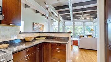 Una cocina moderna con armarios de madera oscura, encimera de mármol y un amplio ventanal que proporciona luz natural.