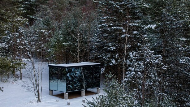 Un moderno edificio de cristal en un bosque nevado.