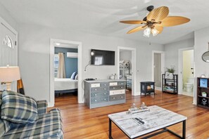 A modern living room with a sofa, a coffee table, a TV, a fireplace, and a ceiling fan.