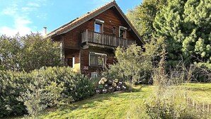 Une cabane en bois dotée d’un balcon, entourée d’une végétation luxuriante.
