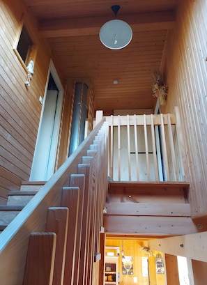 A wooden staircase with a handrail, a ceiling fan, and a view into the room below.